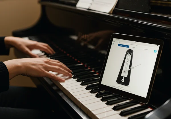 Pianist's hands on piano with online metronome on screen.